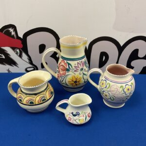 Group of vintage Poole and Honiton pottery jugs with floral designs.