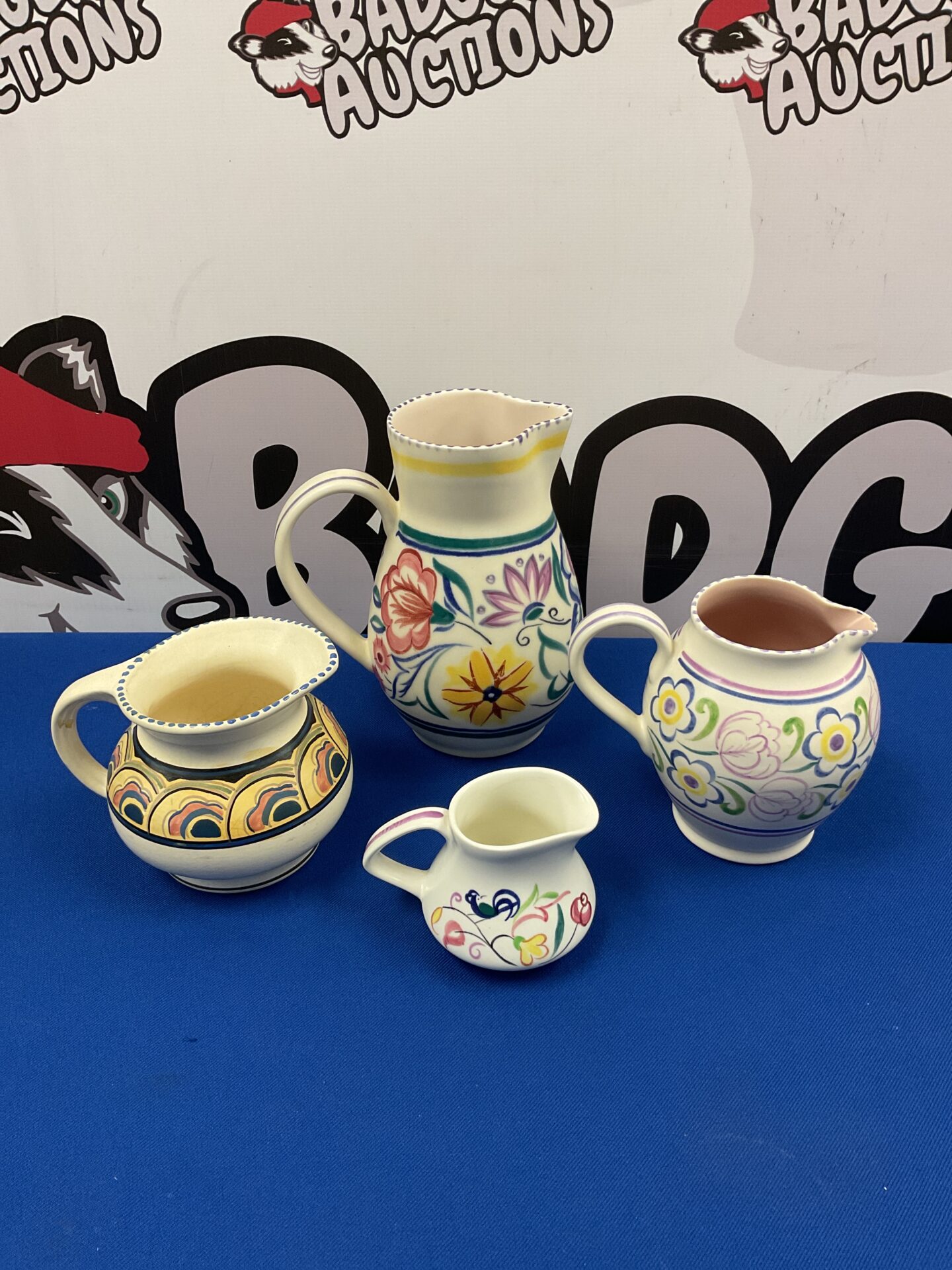 Group of vintage Poole and Honiton pottery jugs with floral designs.