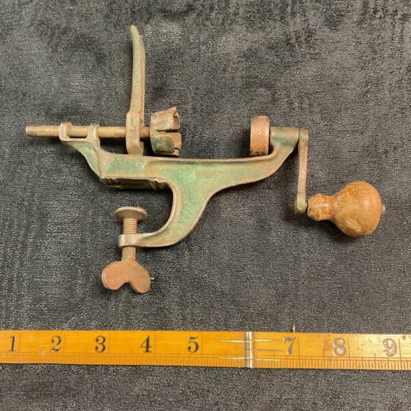 Antique cast iron apple corer with wooden handle, vintage kitchen tool.